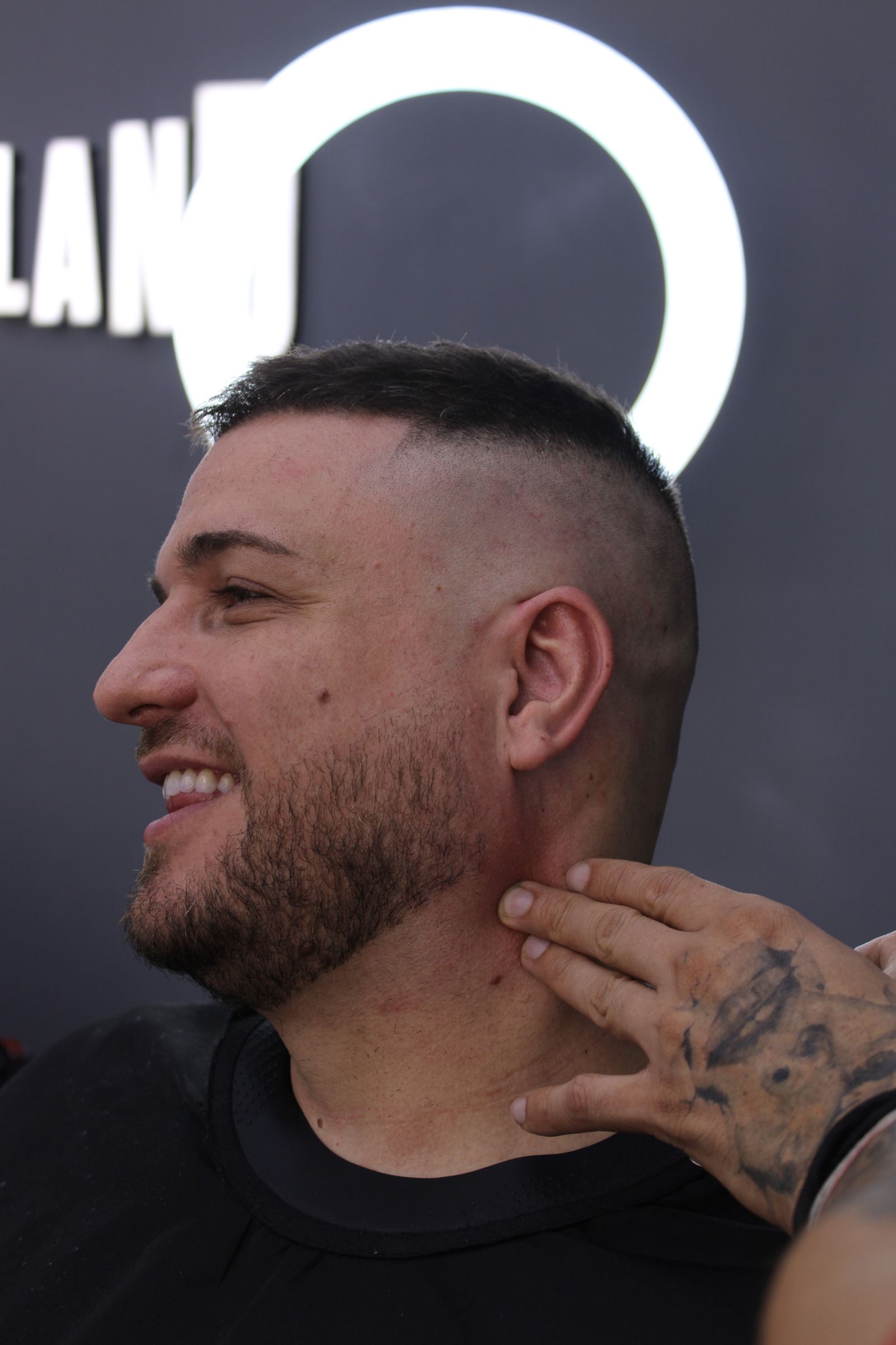 Cliente con corte undercut junto al rótulo de Barberland Premium