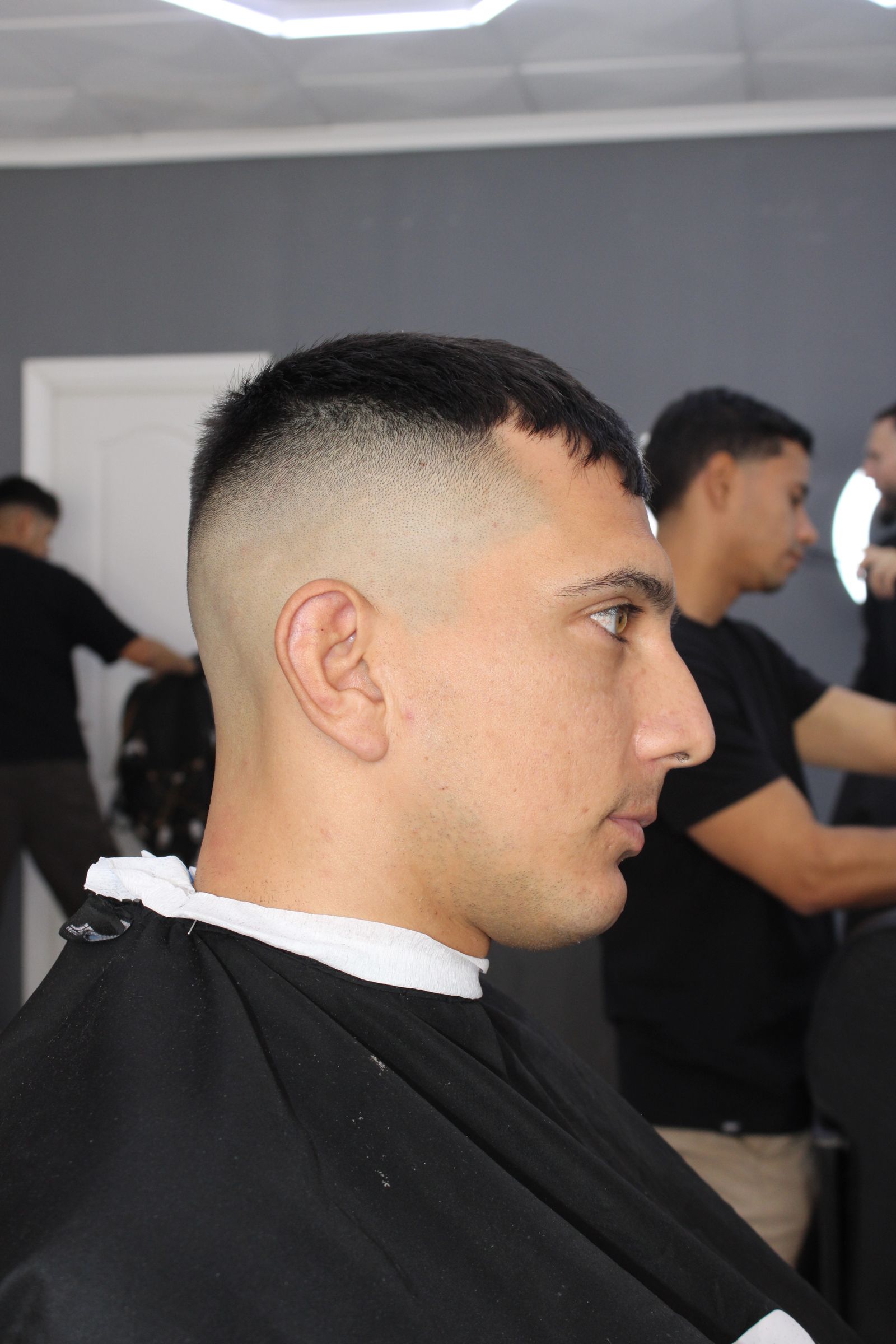 Barbero cortando el pelo desde atrás, corte degradado en proceso