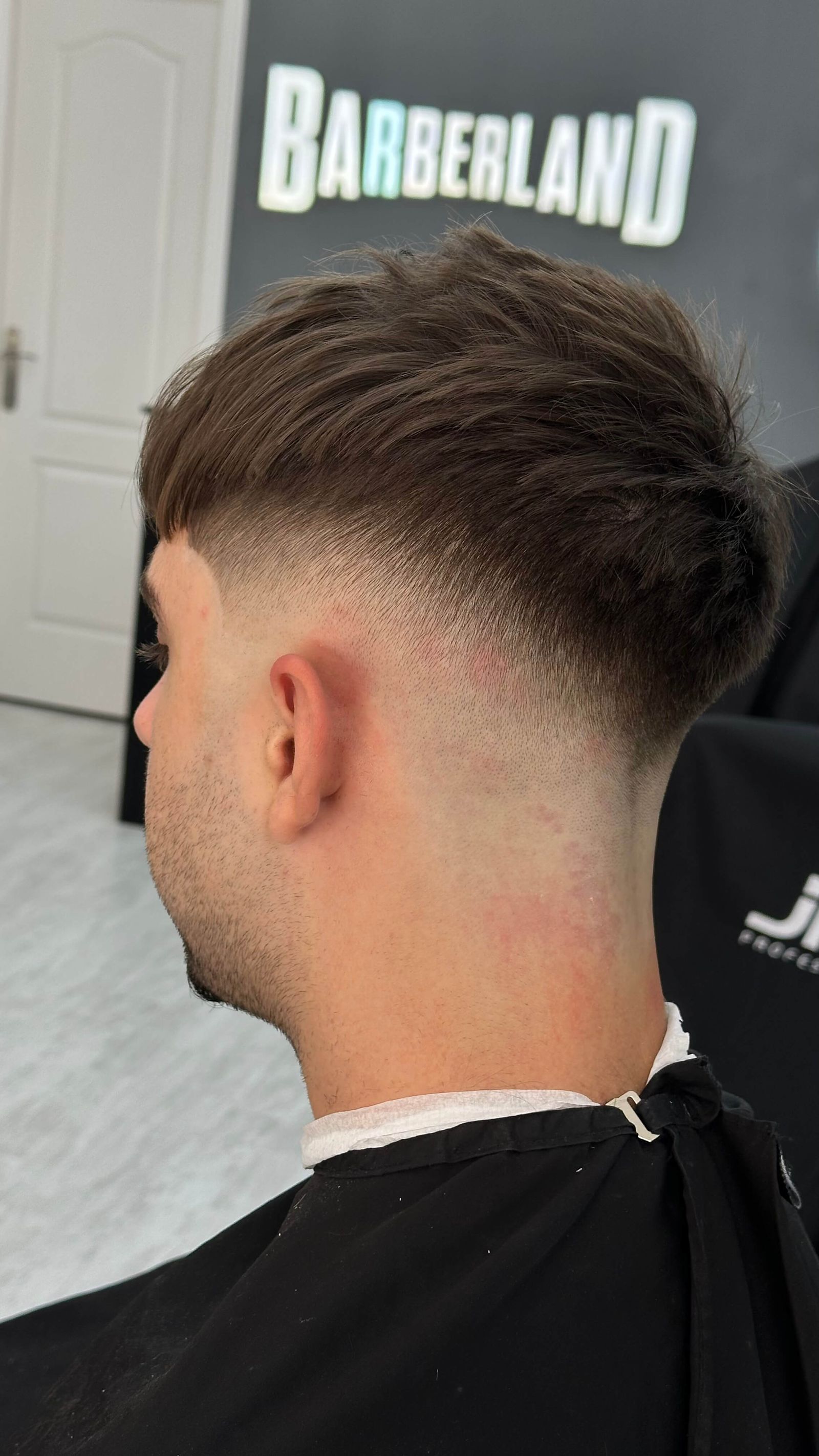 Barbero rociando producto en el pelo de un cliente