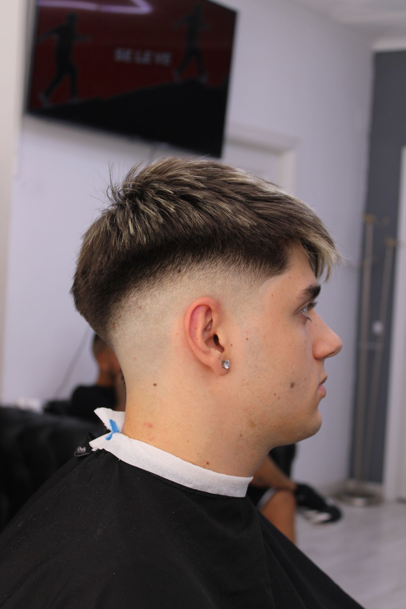 Interior de la barbería Barberland Premium con varios sillones y luces de anillo encendidas