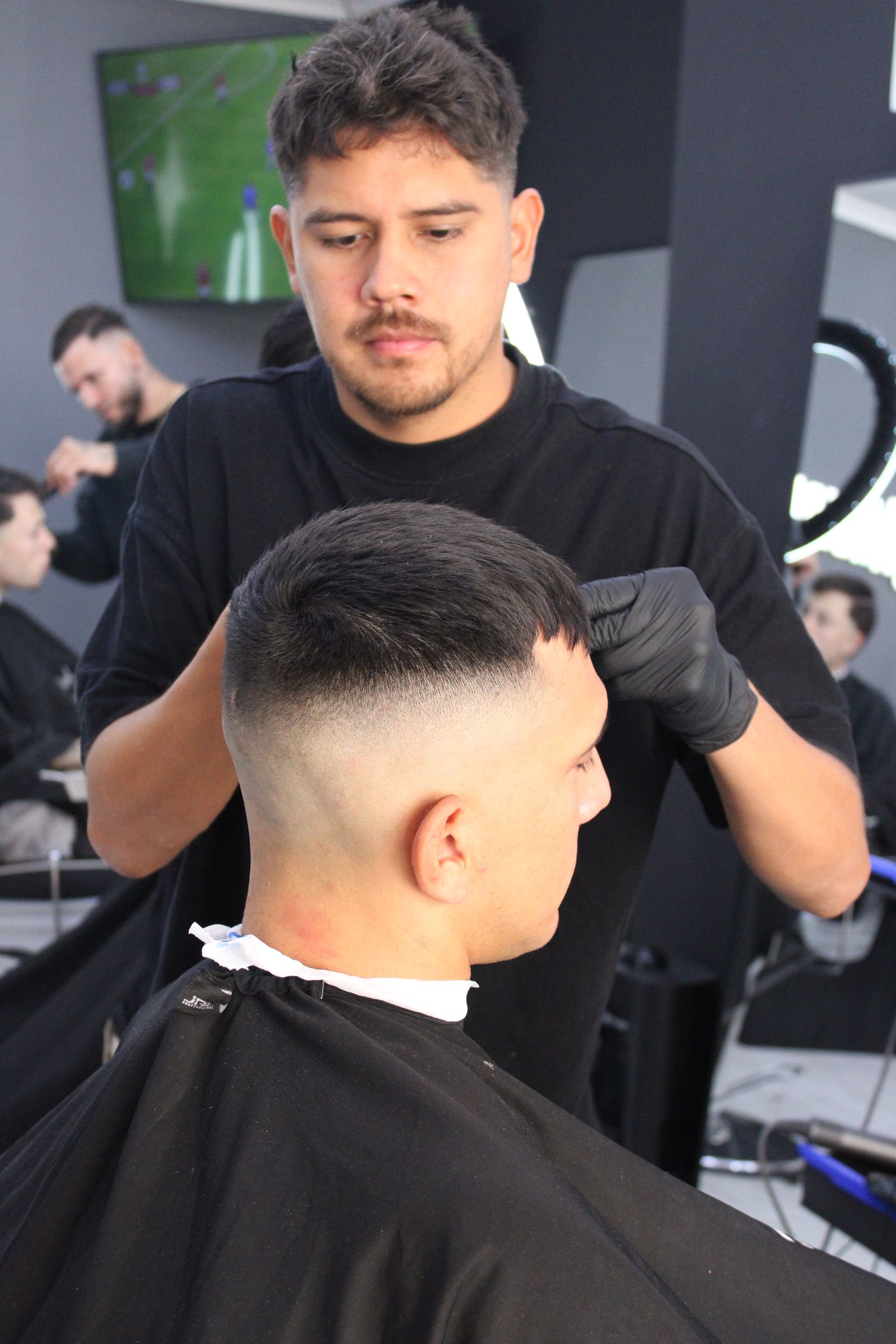 Barbero de Barberland Premium peinando a un cliente desde atrás