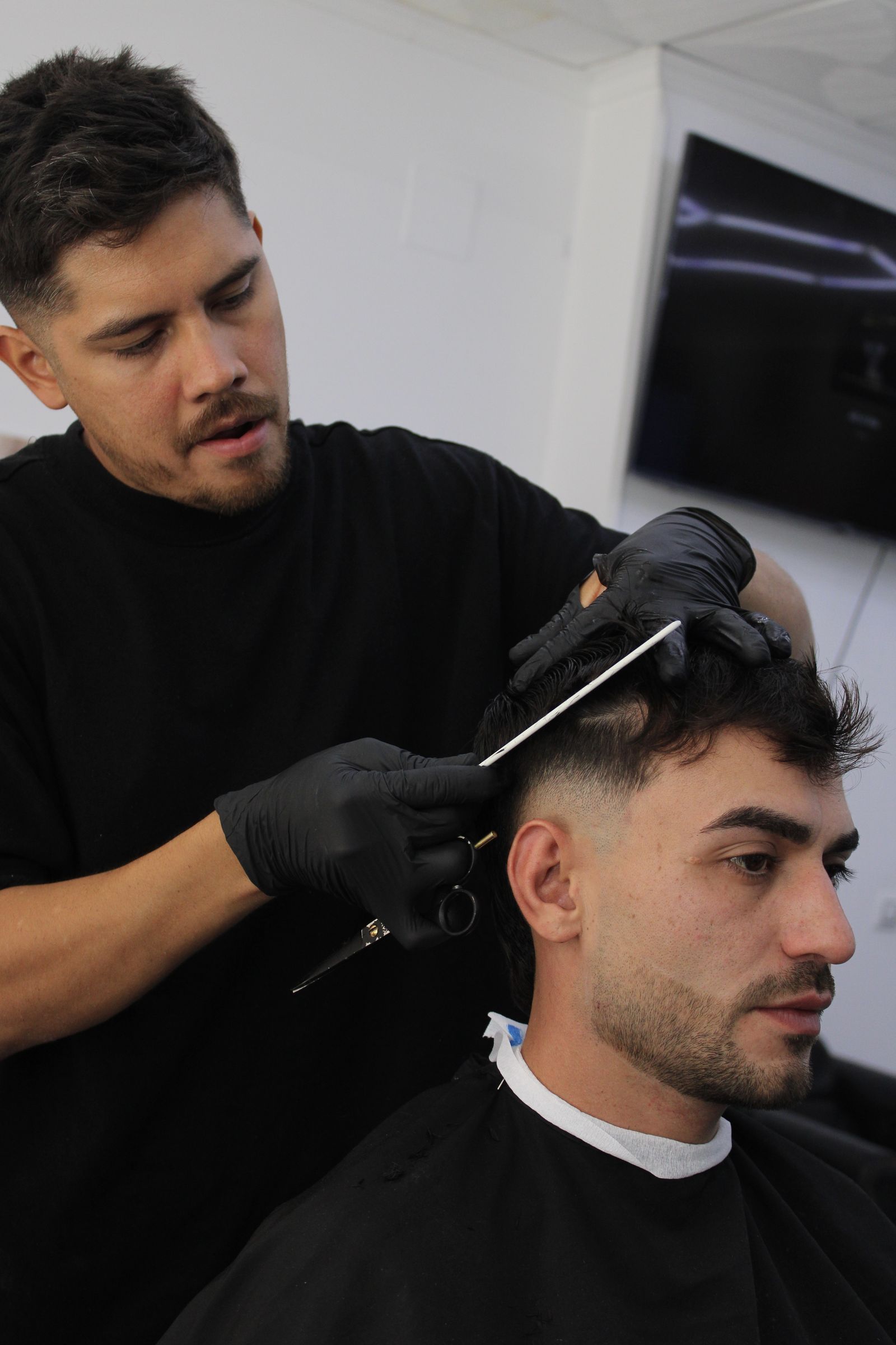 Barbero aplicando la máquina de corte con precisión a un cliente